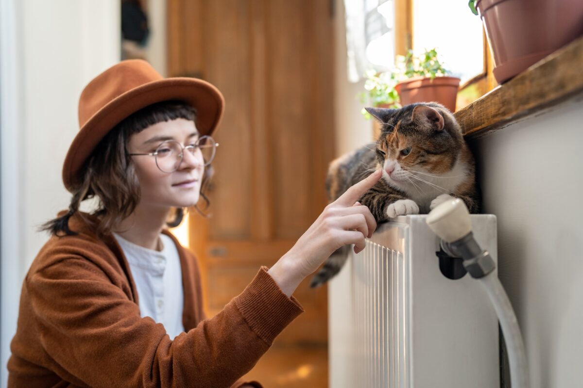 Happy smiling teen girl playing with cat at home