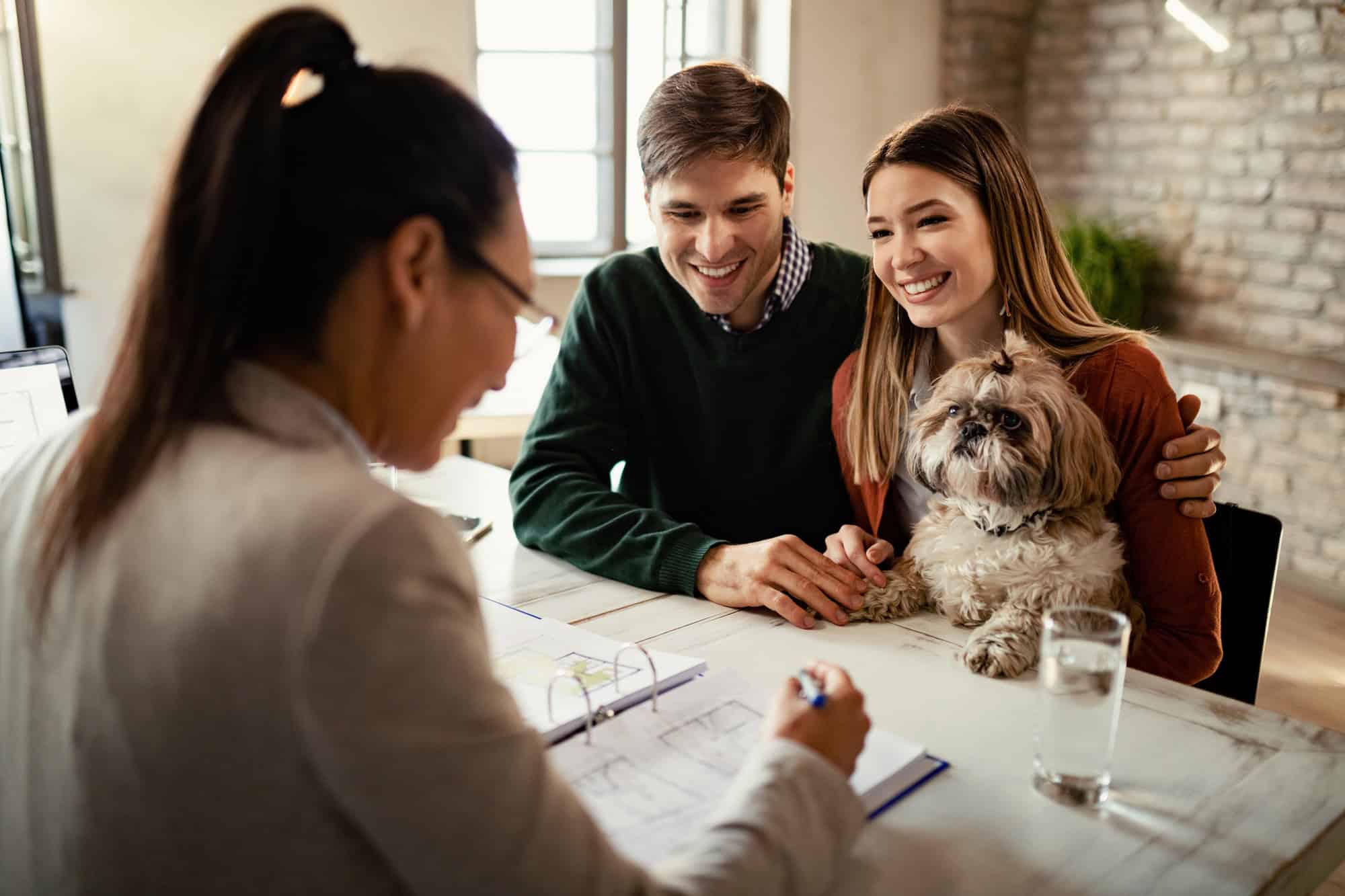 Couple heureux avec un chien en réunion avec un agent d'assurance.