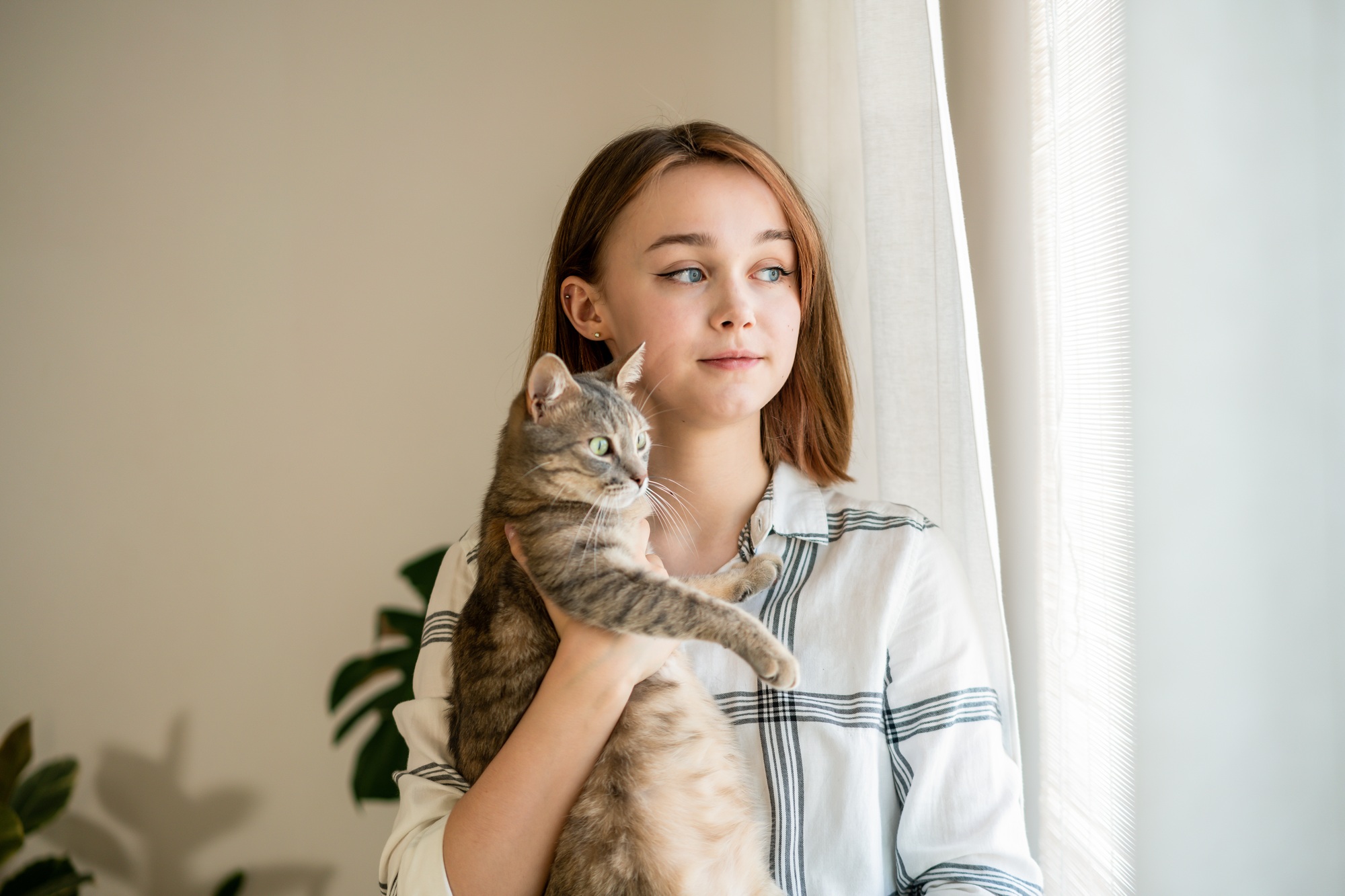 Femme regardant la fenêtre avec un chat.