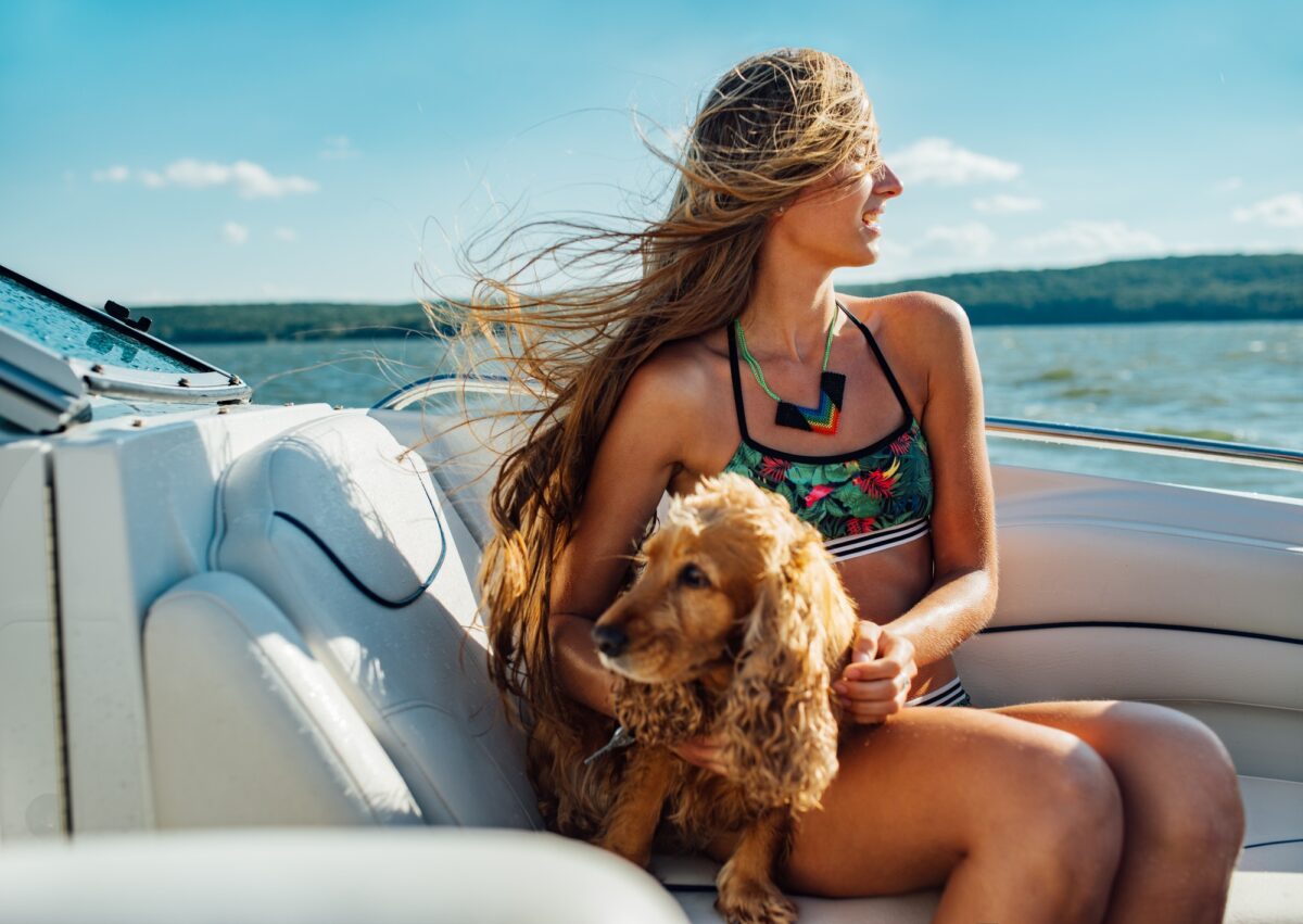 fille aux cheveux longs sur le bateau avec un chien souriant