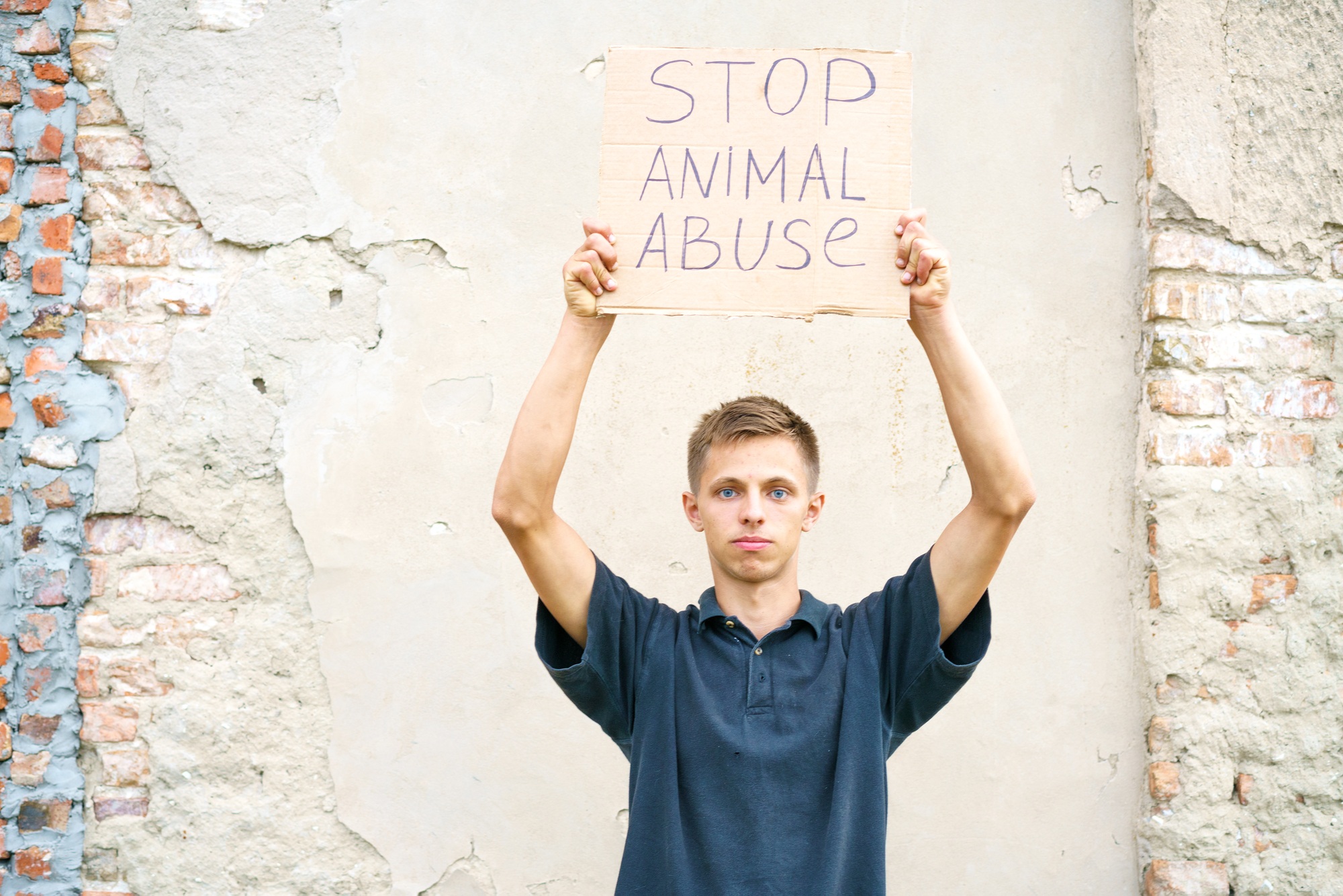 Jeune homme tenant l'inscription "Stop à la maltraitance des animaux" dans sa main.